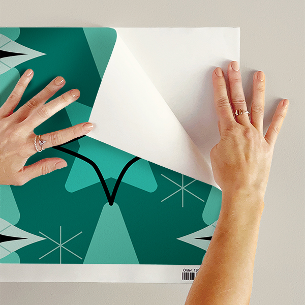 The artwork features a repeating geometric pattern of symmetrical shapes resembling elongated, curved diamonds or petals in various shades of blue and green. Each shape is split vertically with one half filled with a light blue and the other half filled with green or darker blue. The background is a light, almost pastel blue, which provides a soft yet vibrant backdrop. One of the blue shapes near the upper left contains a white starburst element, adding a focal point of brightness to the composition. The overall design conveys a modern, mid-century aesthetic with clean lines and harmonious color contrasts.